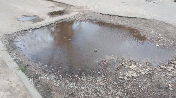 Величезна калюжа посеред дороги заважає людям ходити