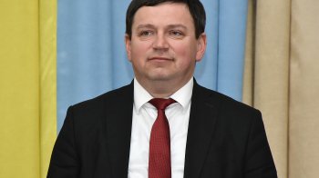 Богдан Буяк стоїть на фоні прапора України