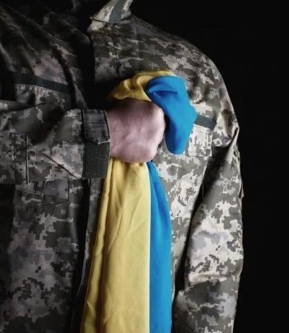 Військовий притискає до грудей український прапор, фото Координаційного штабу з питань поводження з військовополоненими