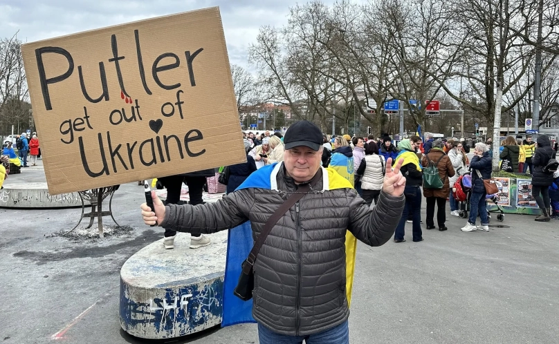 Михайло Тіц позує з плакатом «Путін, забирайся з України» на мітингу у швейцарському в Берні, 24 лютого 2024 року (фото Facebook)