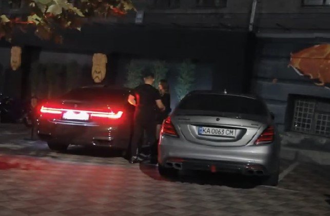 (Чоловік та жінка сідають в автомобіль на львівській реєстрації, припаркований поруч із столичним рестораном Boho. Cкріншот з відео)