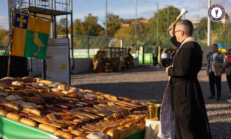 Священник окроплює панно з хліба і ковбаси