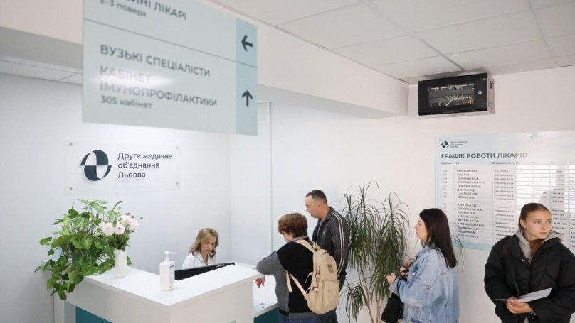 Двоє пацієнтів розмовляють з працівницею на рецепції у Другому медичному об’єднанні Львова, ще двоє – стоять у черзі