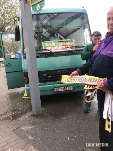 Чоловіки біля автобуса. Один тримає наліпку “Шептицький”